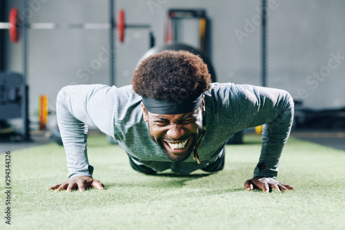 Photography Handsome young Black man struggling with doing push-ups on gym floor