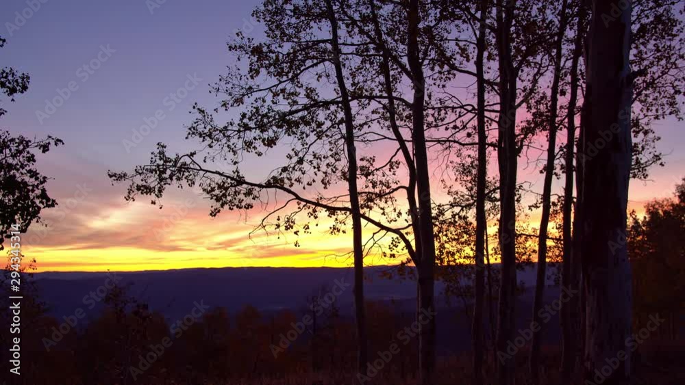 View of colorful sunrise looking through trees on slider slowly moving to the side. View of colorful sunrise looking through trees on slider slowly moving to the side.