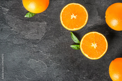 Fresh oranges on dark stone table. Half oranges on table from top view. Tasty oranges fruits. © Milan