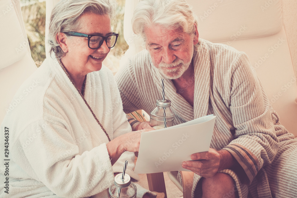 two seniors looking at the menu of the resort and choosing something about that - massage and enjoying together sit two seniors looking at the menu of the resort and choosing something about that - massage and enjoying together sit