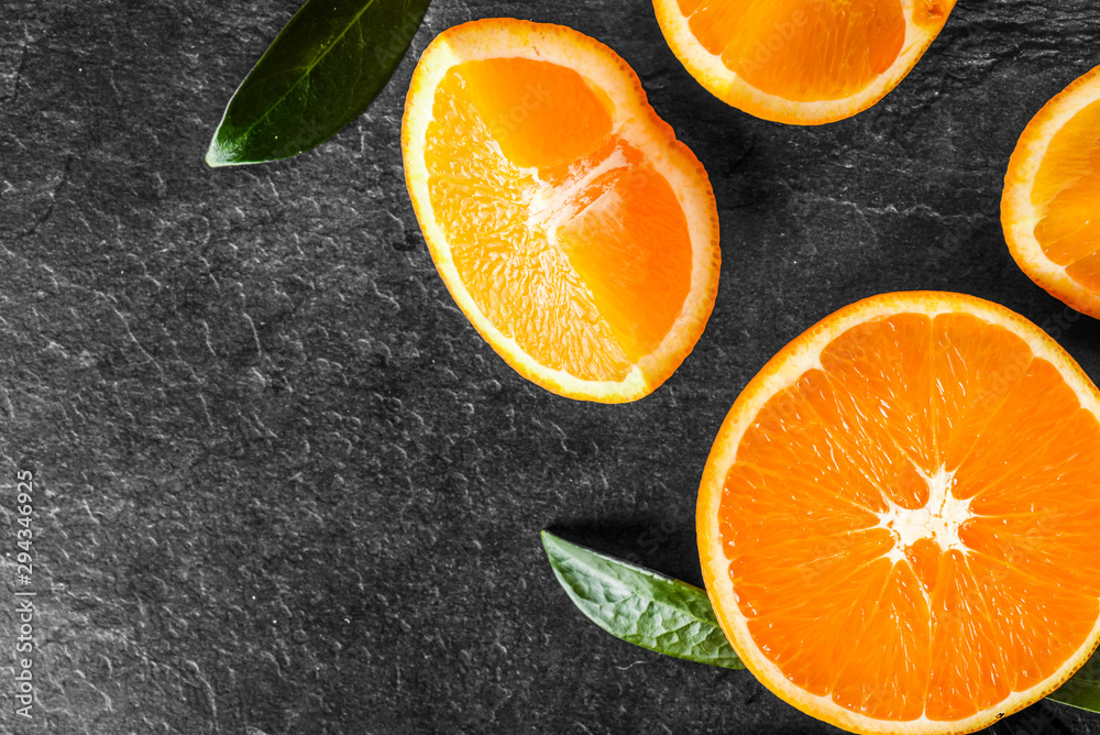Fresh ripe tasty oranges on stone table. Orange on black background. Cut half oranges from top view. Fresh ripe tasty oranges on stone table. Orange on black background. Cut half oranges from top view.