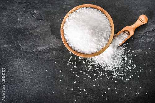 Photos Salt in wooden olive bowl with scoop on stone table
