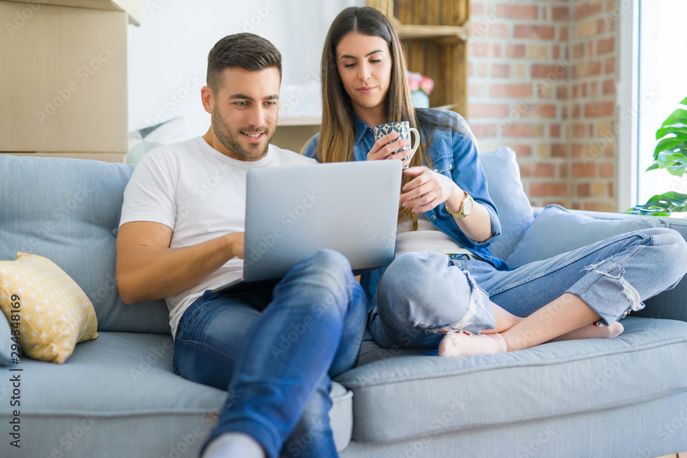 Young couple moving to a new home relaxing sitting on the sofa using computer laptop, smiling happy for moving to new apartment Young couple moving to a new home relaxing sitting on the sofa using computer laptop, smiling happy for moving to new apartment