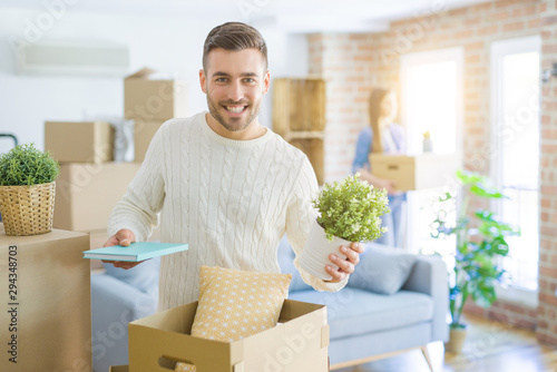 Young couple moving to a new home  handsome man smiling moving cardboard box