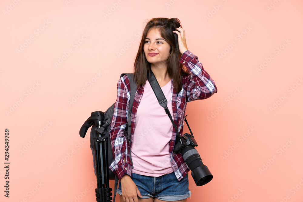 Young photographer girl over isolated pink background having doubts and with confuse face expression Young photographer girl over isolated pink background having doubts and with confuse face expression
