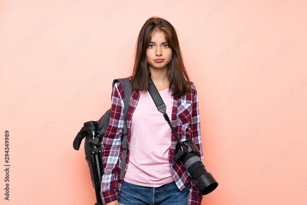 Young photographer girl over isolated pink background sad Young photographer girl over isolated pink background sad