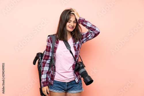 Young photographer girl over isolated pink background having doubts with confuse face expression