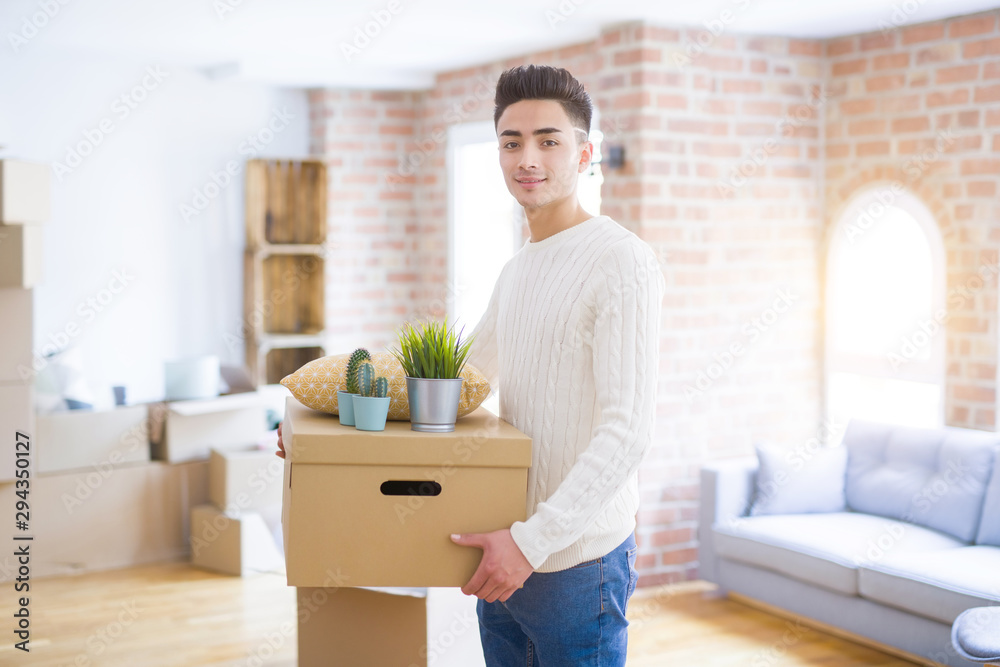 Young man smiling holdig cardboard box, happy moving to a new house Young man smiling holdig cardboard box, happy moving to a new house