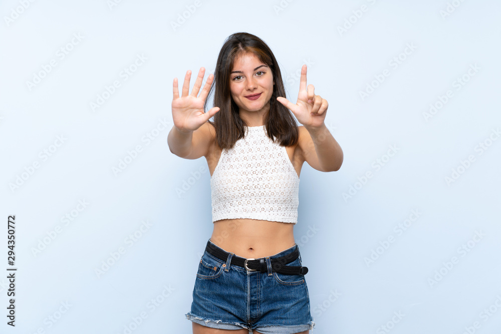 Young woman over isolated blue background counting seven with fingers Young woman over isolated blue background counting seven with fingers