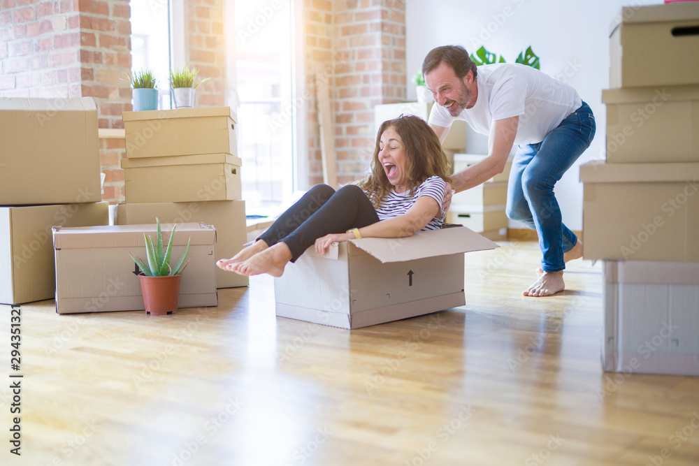 Middle age senior romantic couple having fun riding inside of cardboard, excited and smiling happy for moving to a new home Middle age senior romantic couple having fun riding inside of cardboard, excited and smiling happy for moving to a new home