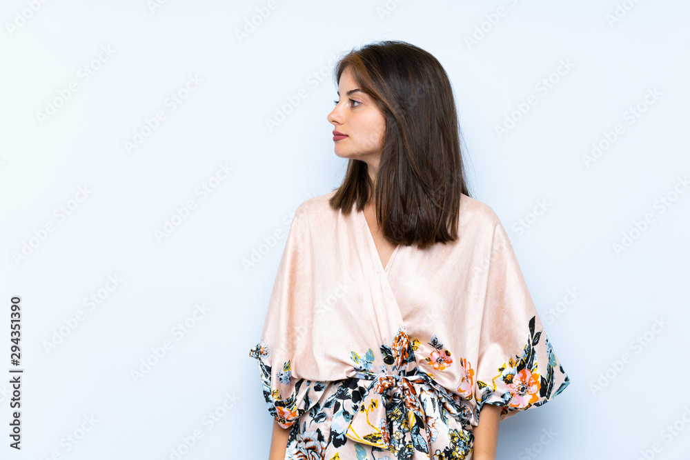 Caucasian girl with kimono over isolated blue background looking side Caucasian girl with kimono over isolated blue background looking side