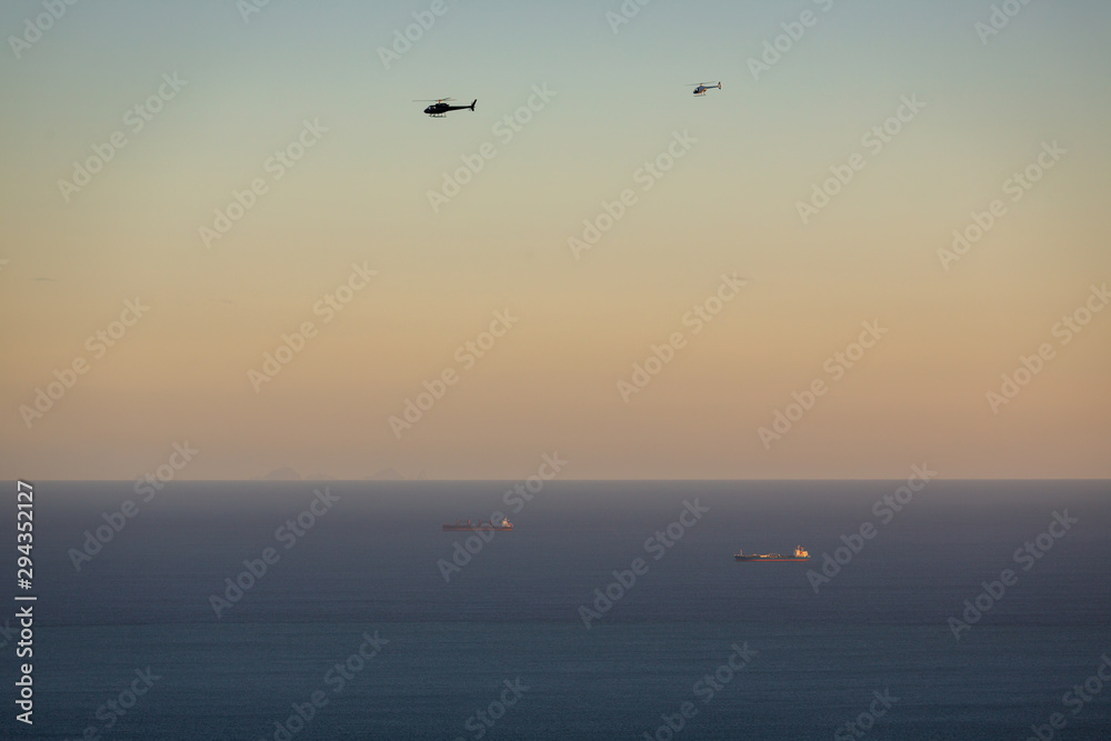 Helicopters and ships at dawn over the ocean