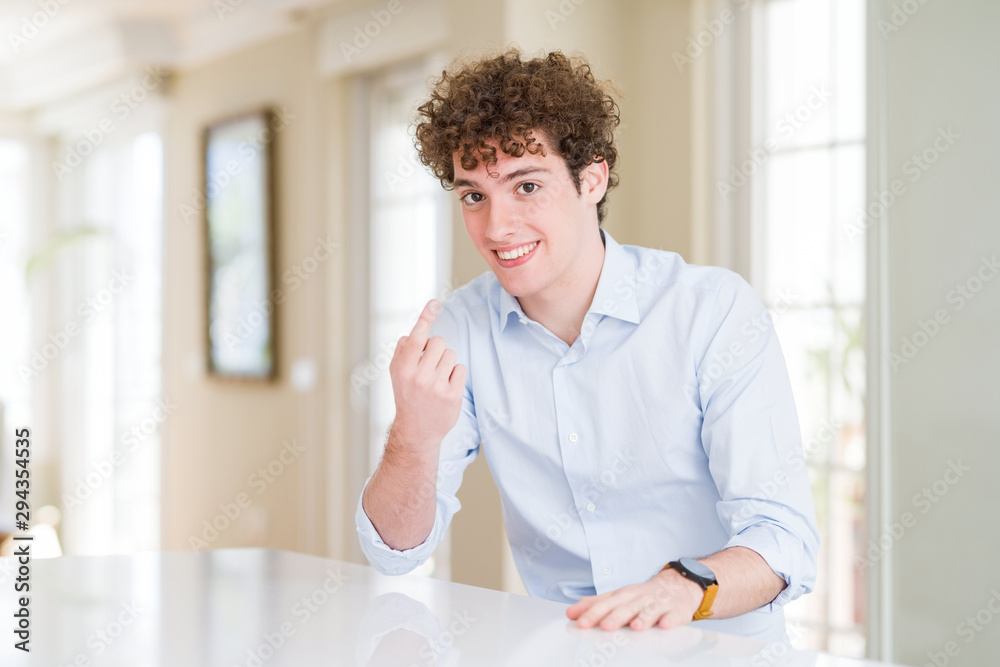 Young business man with curly read head Beckoning come here gesture with hand inviting welcoming happy and smiling