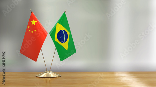 Photography Chinese and Brazil flag pair on a desk over defocused background