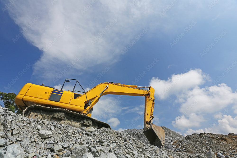 Yellow backhoe working scoop rock dig a large well or Industrial excavator loading soil material from the garden Yellow backhoe working scoop rock dig a large well or Industrial excavator loading soil material from the garden