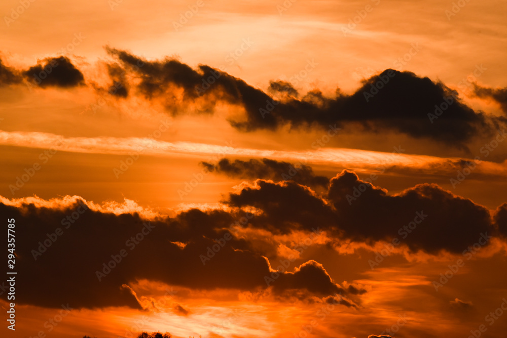 Beautiful orange sunstet with heavy or black clouds on fiery sky.