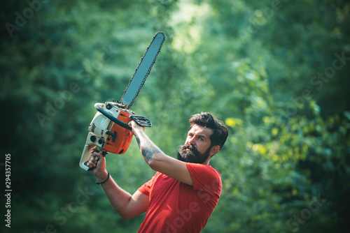 Woodworkers lumberjack. Lumberjack on serious face carries chainsaw. Man doing mans job. Lumberjack worker walking in the forest with chainsaw.