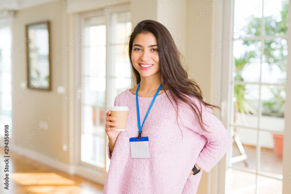 Young beautiful business woman wearing an id card drinking a cup of coffee Young beautiful business woman wearing an id card drinking a cup of coffee