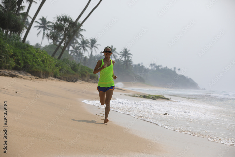 Fitness healthy lifestyle young woman running on tropical beach during sunrise in the morning