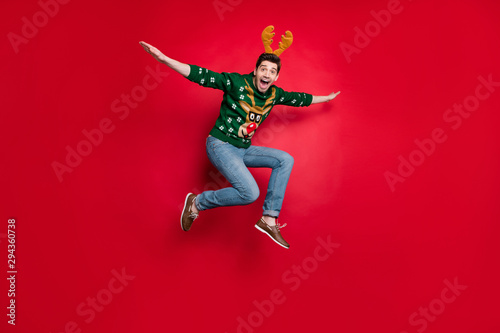 Full length photo of funny jumping guy spread arms flying fast to sale x-mas shopping wear pullover with ugly ornament isolated red color background © deagreez