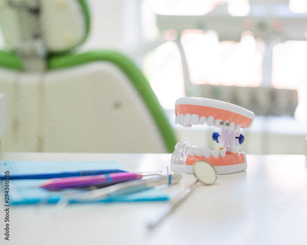 Sterile instruments are in the dentist's office. A mirror, tweezers, a probe and a jaw layout are on the orthodontist's table. Oral hygiene, caries prevention, examination. Sterile instruments are in the dentist's office. A mirror, tweezers, a probe and a jaw layout are on the orthodontist's table. Oral hygiene, caries prevention, examination.