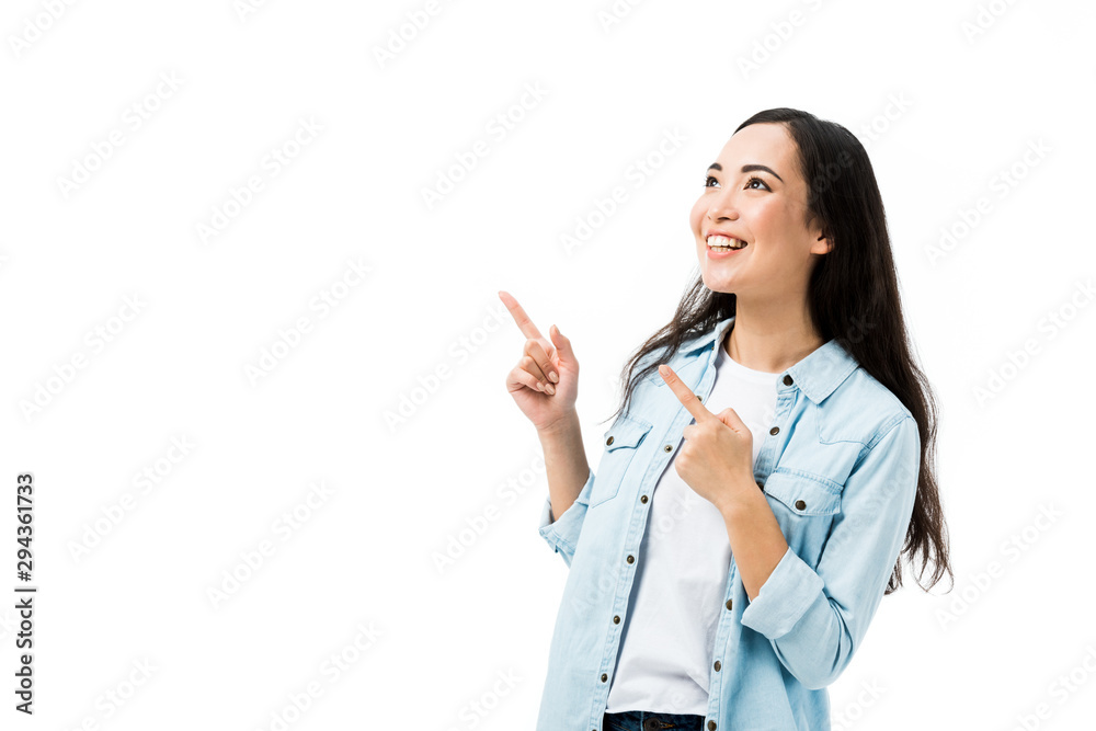 attractive and smiling asian woman in denim shirt pointing with fingers isolated on white attractive and smiling asian woman in denim shirt pointing with fingers isolated on white