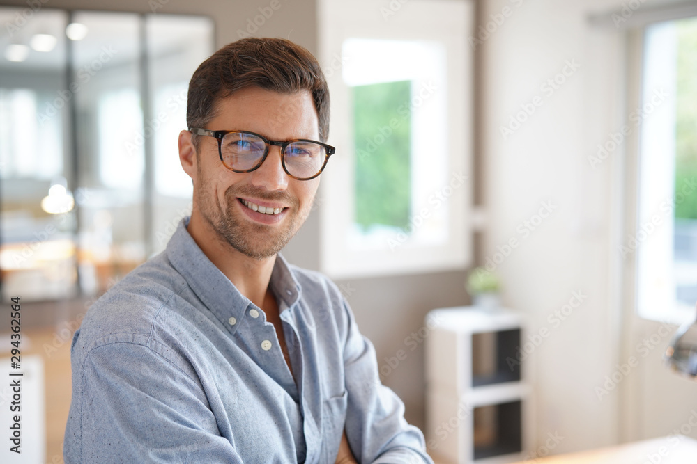 Cheerful man with eyeglasses standing in office Cheerful man with eyeglasses standing in office