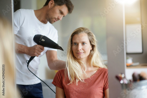 Hairdresser at home brushing and drying woman's hair
