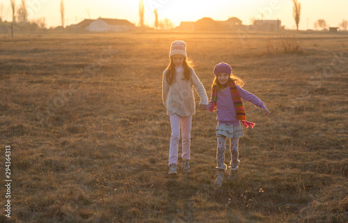 Young adorable children siblings playing outdoors, happy sisters having fun in field