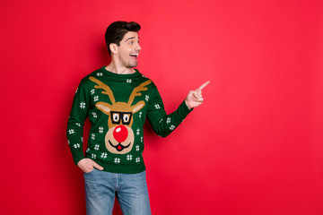 Profile side photo of excited funny man in deer reindeer jumper look point index finger at copyspace isolated over red color background