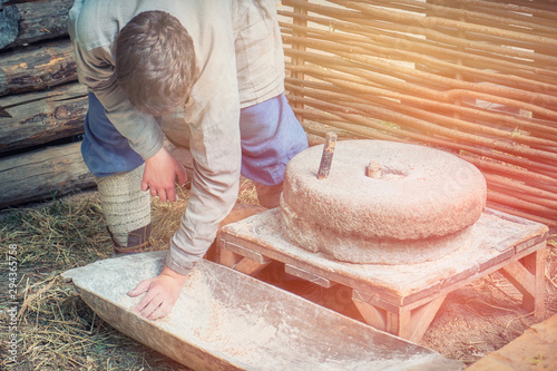 Man to grind flour on the hand mills. Rustic life for the production of bread by grinding grains into flour.