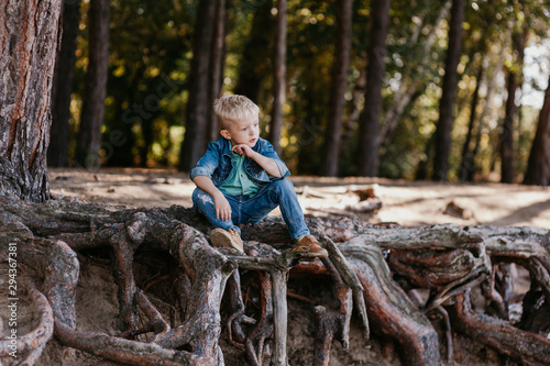 Cute baby boy sitting in summer park. Outdoor portrait.