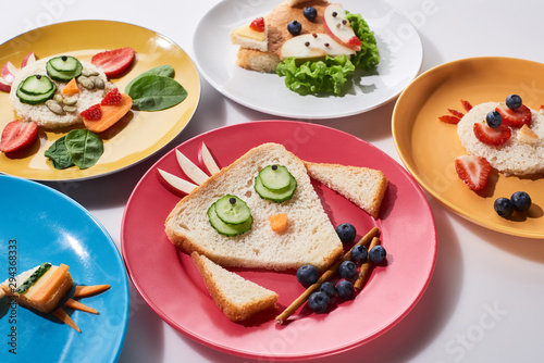 plates with fancy animals made of food for childrens breakfast on white background