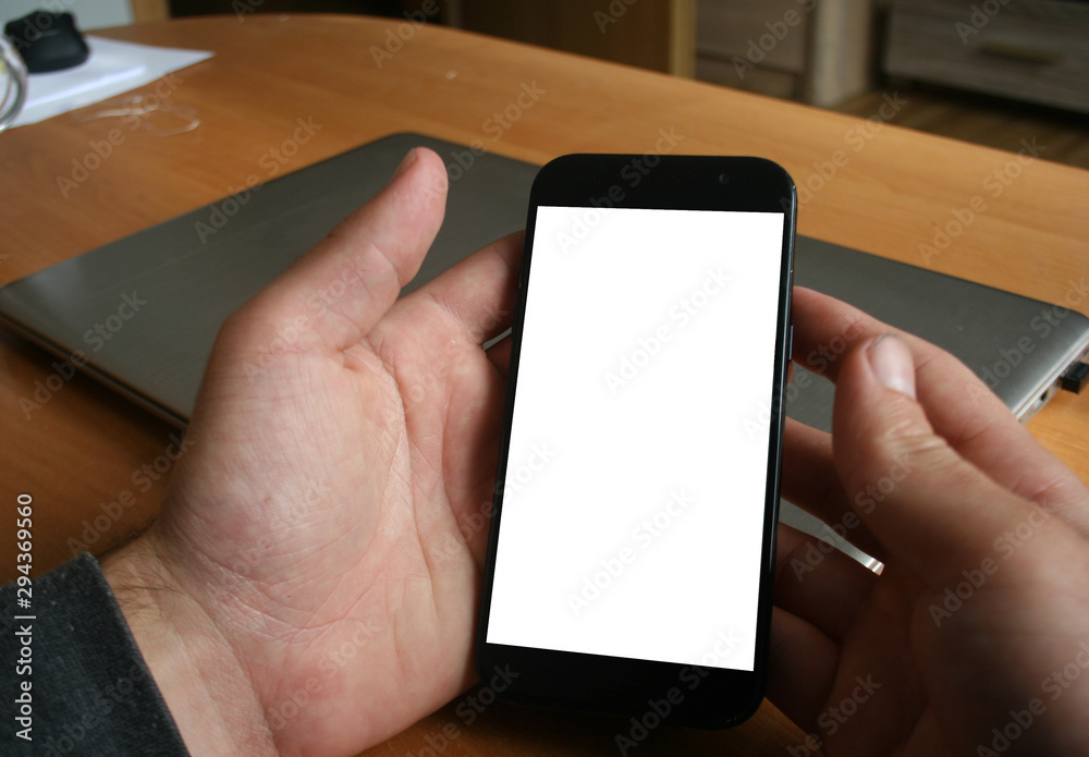 mockup image screen smartphone in hand with blank space for text,using laptop contact business searching information in workplac
