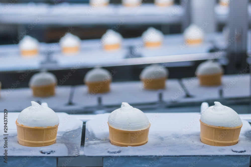 Icecream automatic production line - conveyor belt with ice cream cones at modern food processing factory. Food dairy industry, manufacturing, engineering and automated technology equipment concept