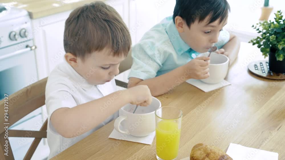 Two baby boys eating muesli for breakfast in the kitchen Two baby boys eating muesli for breakfast in the kitchen