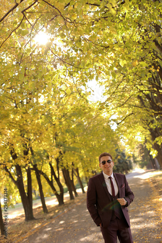 Happy laughing man businessman walking in autumn Park in nice Sunny warm weather. © Ievgen Tytarenko