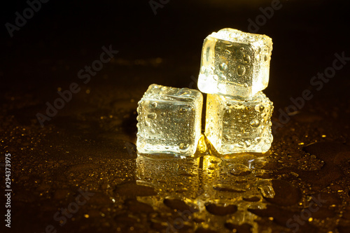 ice cubes on a reflections yellow light. © peterkai