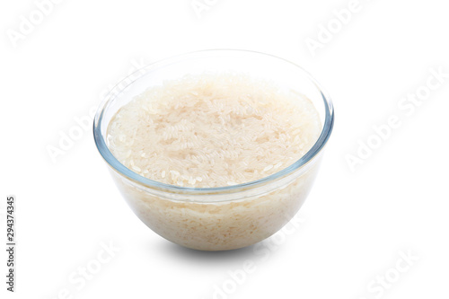 Bol de cristal con arroz crudo sobre fondo blanco, vista cenital. Glass bowl with raw rice on white background, overhead view.