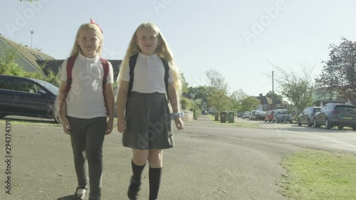 Pre teen twin caucasian girls walking to school