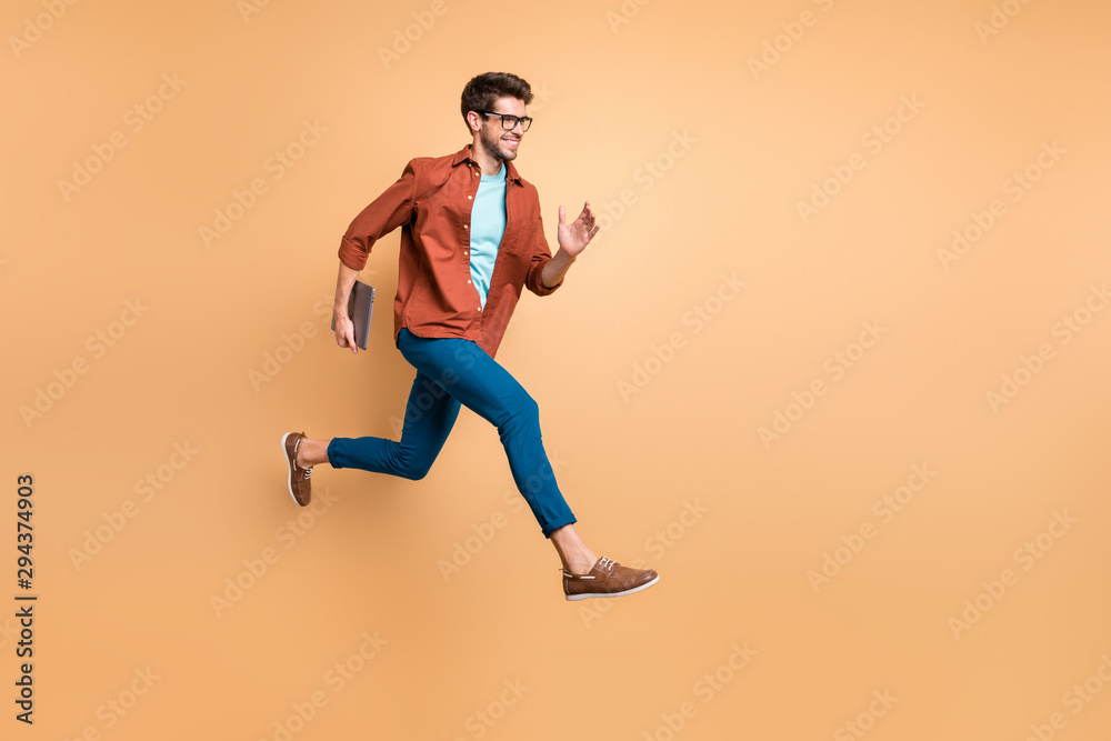 Full length body size view of his he nice attractive cheerful glad guy leader jumping in air carrying laptop running fast late hurry-up meeting appointment isolated over beige color pastel background