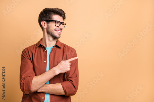 Close-up portrait of his he nice attractive cheerful cheery glad content brunet guy pointing forefinger aside copy space advice advert ad decision isolated over beige color pastel background