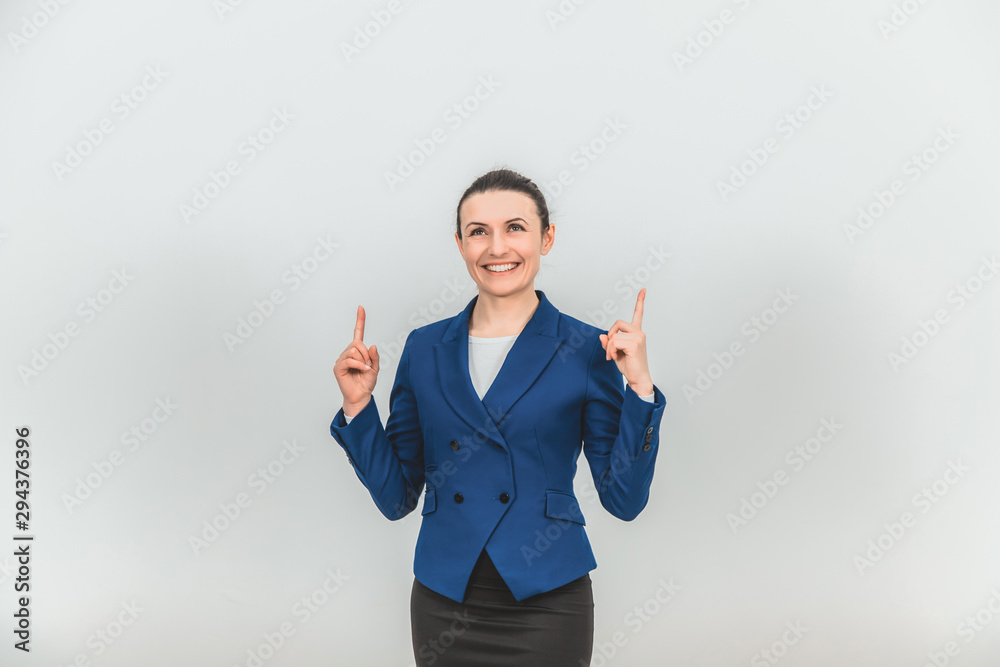 Smiling beautiful teacher standing, pointing her fingers up at the copy space for text or product and looking up. Smiling beautiful teacher standing, pointing her fingers up at the copy space for text or product and looking up.