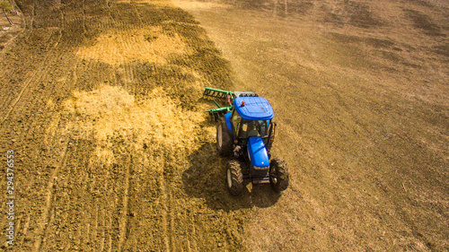 aerial view drone of blue tractor with plow in operation in the field