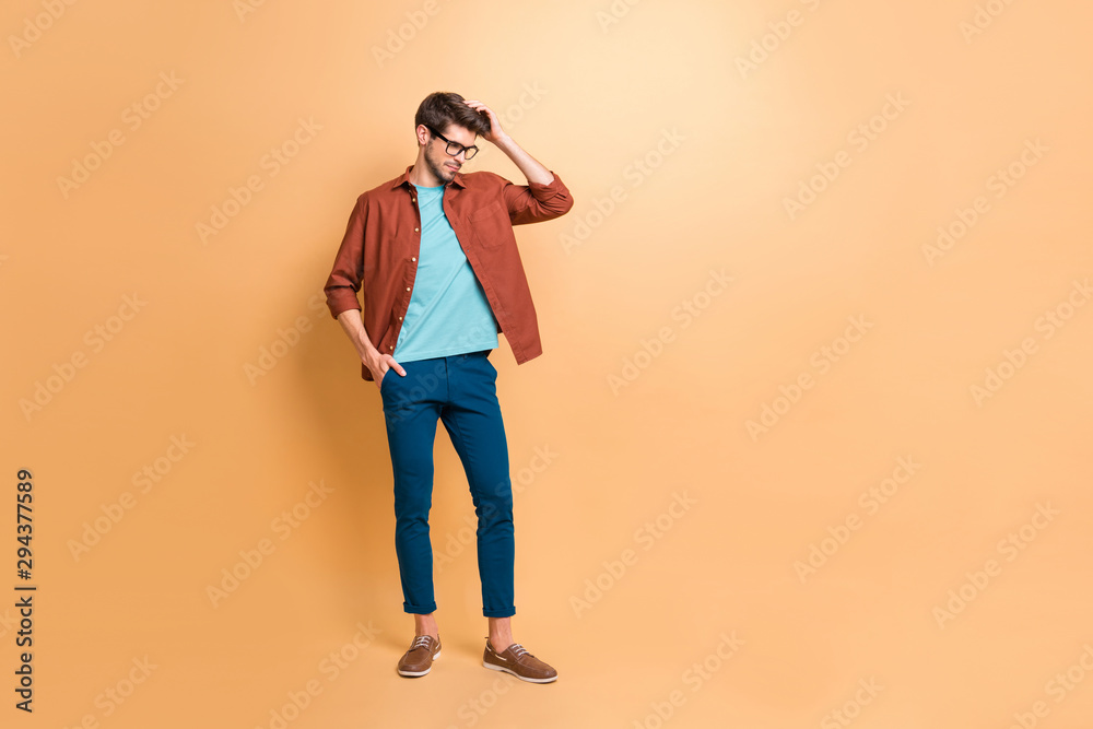 Full length body size view of his he nice attractive fashionable brunette guy hipster posing touching fixing hair isolated over beige color pastel background Full length body size view of his he nice attractive fashionable brunette guy hipster posing touching fixing hair isolated over beige color pastel background