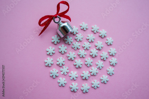 Christmas ball, with a red ribbon pendant, made of snowflakes on a soft pink background. Copy space