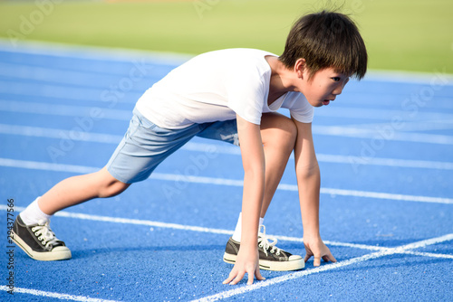 Young boy running on blue track