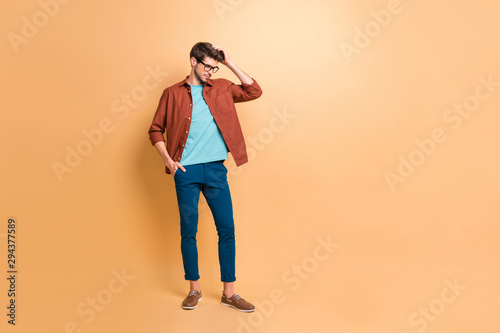 Full length body size view of his he nice attractive fashionable brunette guy hipster posing touching fixing hair isolated over beige color pastel background © deagreez