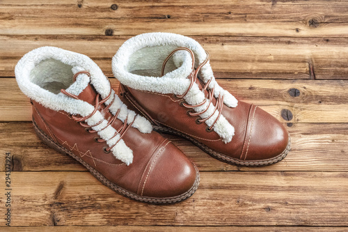 A pair of winter brown boots on a wooden background.