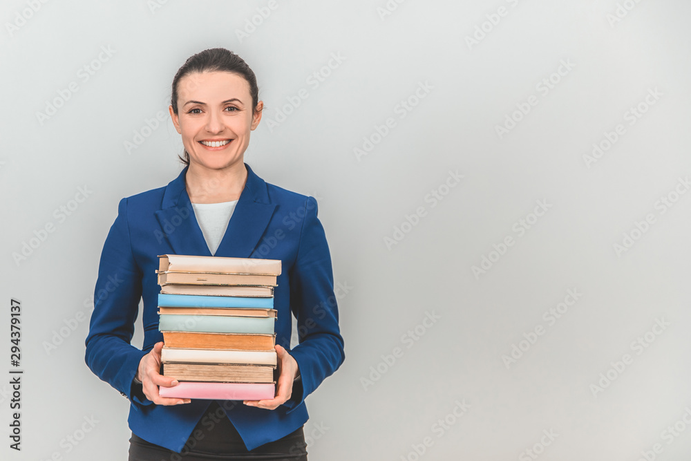 Lovely female teacher holding a stack of colorful books, smiling. Lovely female teacher holding a stack of colorful books, smiling.